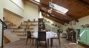 Un área de comedor con techo alto de madera, una escalera y un mueble verde.