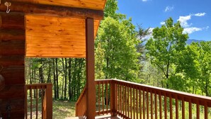 A wooden cabin with a porch and a view of a forest. - Elkmont Views - 1BR/New Hot Tub/New Firepit/Grill/Sleeps 6 (Gatlinburg)