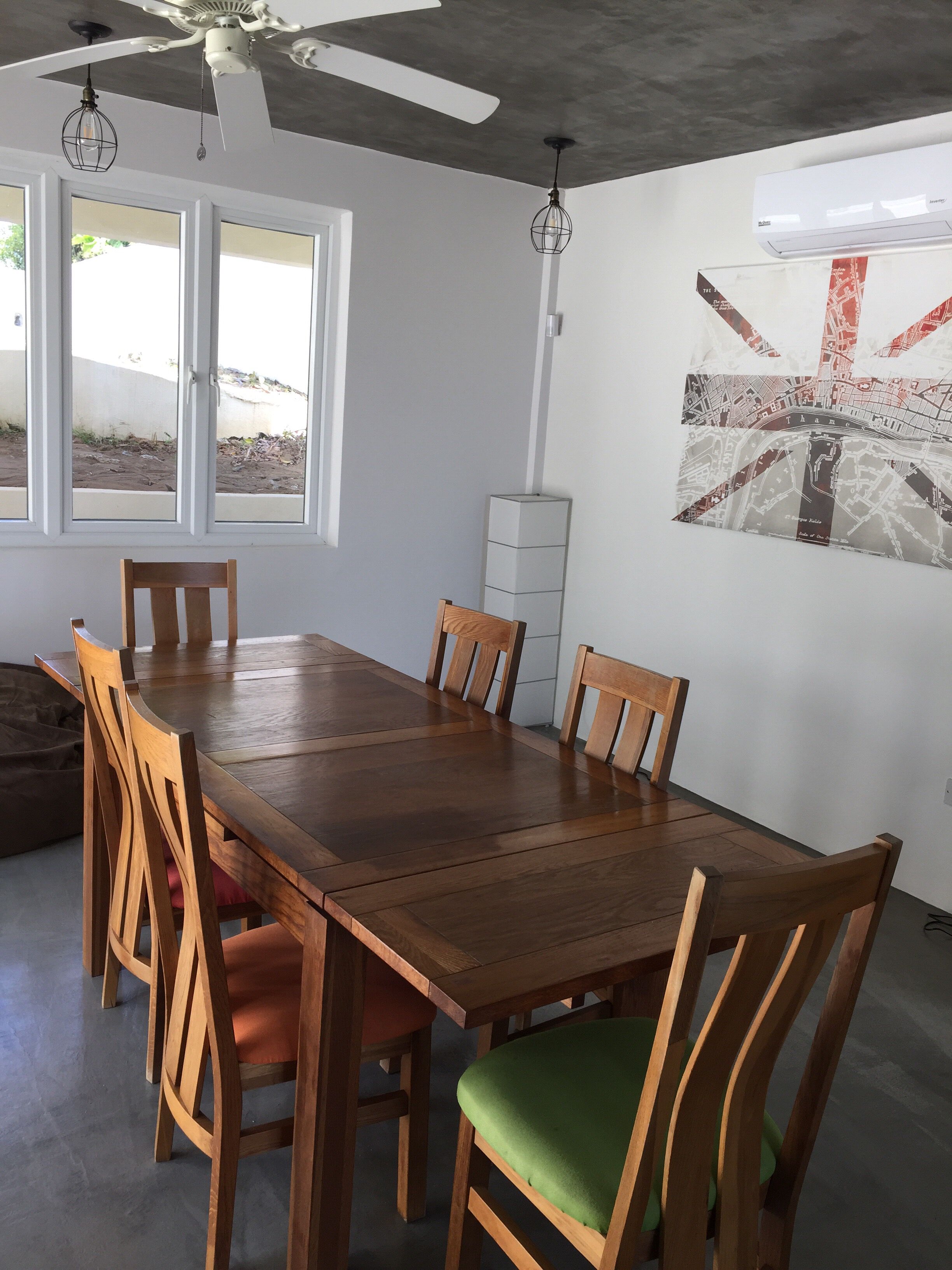 A dining area with a wooden table and chairs, a ceiling fan, and a map on the wall.