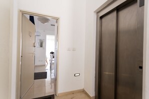 A hallway with a door leading to a room, a light switch, and a power outlet.