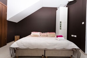 Relax in this stylish bedroom with a plush bed, featuring a white quilted headboard and comfortable pillows.