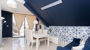 Un salon moderne comprenant un coin repas, un canapé bleu et un mur orné d’un motif.