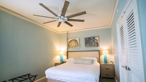 Una camera da letto con un letto, due lampade sui comodini, una ventola a soffitto e una porta con persiane a lamelle.