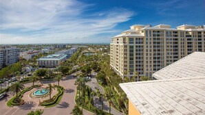 Un hotel di grandi dimensioni con area piscina, circondato da palme e altri edifici.