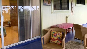 A covered outdoor area with a sliding glass door, wicker furniture, and a tropical-themed rug.