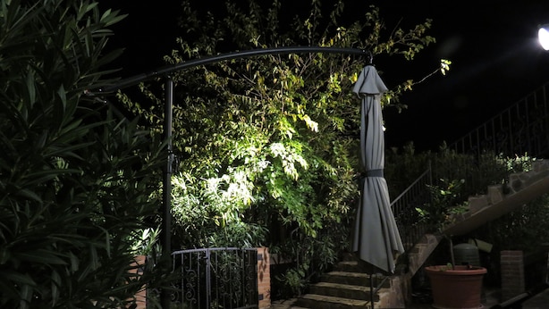 A patio area with a stone floor, a metal railing, and a wooden bench.