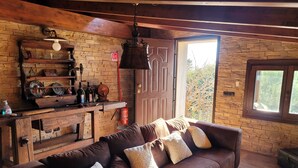 A cozy living room with a brown leather sofa, patterned cushions, a wooden coffee table, and a brick wall.