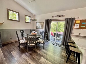 Een eetruimte met een ronde tafel en stoelen, een 'welcome'-bord en een prikbord met een 'guest'-bord.