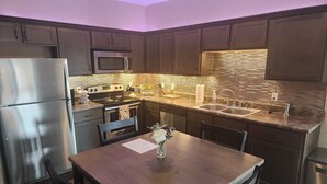 A modern kitchen with dark wooden cabinets, stainless steel appliances, a granite countertop, and a dining table with chairs. - 9th St. Beals Loft Downtown Columbia (Columbia)