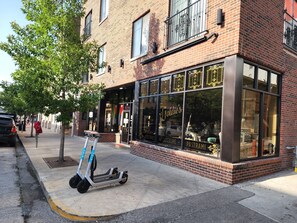 Ein Schaufenster mit großen Fenstern, eine Schilder für 'Joldie's Bagels & Deli' und ein abgestellter Elektroscooter.