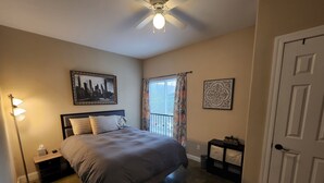 A bedroom with a bed, a nightstand, a floor lamp, a ceiling fan, and a door. - 9th St. Beals Loft Downtown Columbia (Columbia)