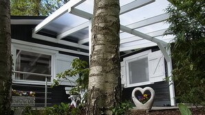 A house with a covered porch, a heart-shaped planter with flowers, and a signboard. - Idyllic holiday home on the forest and lake in Klingberg (Klingberg)