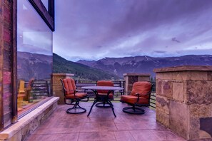 A patio with a table and four chairs, overlooking a mountainous landscape.