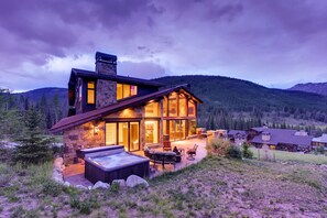 A large stone house with a hot tub and outdoor seating, surrounded by mountains. - Snow Maker Manor: True Ski-In/Out & Dogs Welcome! Hot Tub, Theater, Grill (Copper Mountain)