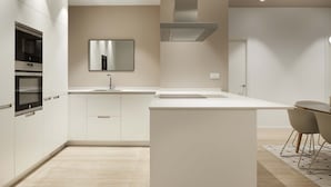 A modern kitchen with white cabinetry, a central island, and a dining area with two chairs. - Avenida Suite by FeelFree Rentals (San Sebastián)