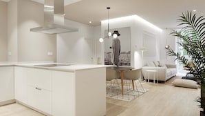 A modern kitchen with white cabinetry, a central island, and a dining area with a table and chairs. - Avenida Suite by FeelFree Rentals (San Sebastián)