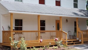A two-story house with a porch, a front door, and a small garden area with plants and flowers. - Beautiful 3 Bedroom House Close To Richmond Raceway (Richmond)