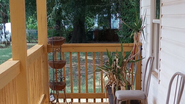 A wooden deck with a railing, a table with chairs, and potted plants. - Beautiful 3 Bedroom House Close To Richmond Raceway (Richmond)
