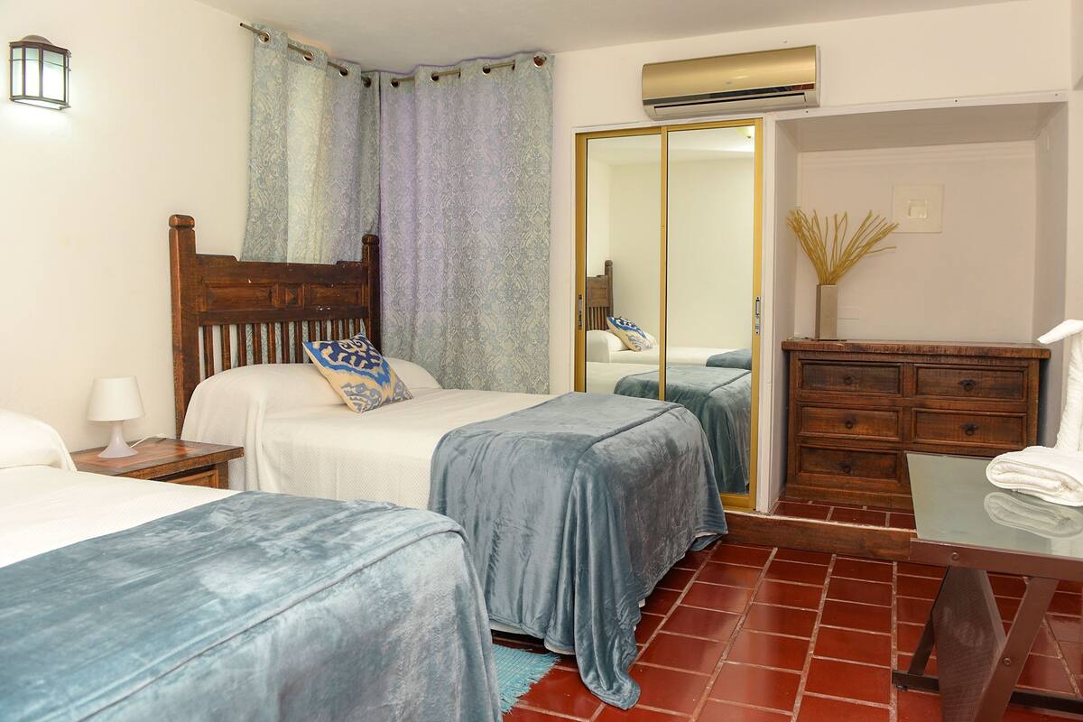 A hotel room with two beds, a wooden headboard, a nightstand, a dresser, and a mirror.