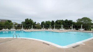 A rectangular swimming pool with a concrete deck, surrounded by white lounge chairs and umbrellas. -  Quiet Bethany Beach Condo   -  Pool • Tennis • Sleeps 8 • 2 Miles to Beach (Frankford)