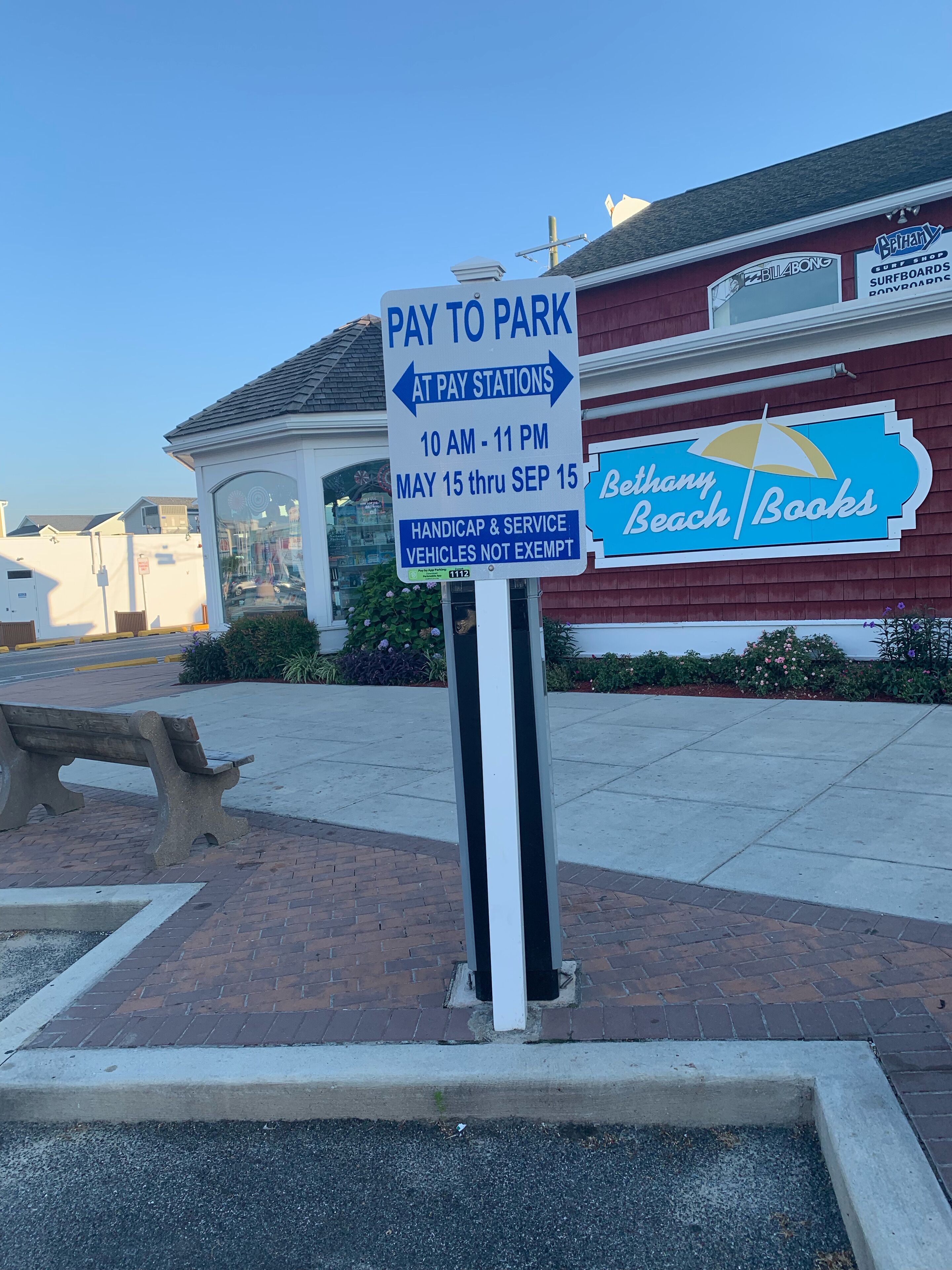 A 'Pay to Park' sign with directional arrows and operating hours.
