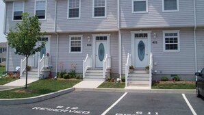 A two-story building with a symmetrical facade, numbered units 612 and 611, and a parking area marked "RESERVED." -  Quiet Bethany Beach Condo   -  Pool • Tennis • Sleeps 8 • 2 Miles to Beach (Frankford)