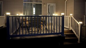 A covered outdoor deck with a railing, a table, and chairs. -  Quiet Bethany Beach Condo   -  Pool • Tennis • Sleeps 8 • 2 Miles to Beach (Frankford)