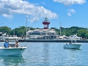 Un port de plaisance avec des bateaux amarrés, un phare imposant et un bâtiment doté d’un balcon.