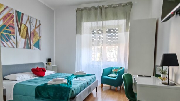 Une chambre d’hôtel moderne avec deux lits, un bureau, une chaise et une grande fenêtre avec des rideaux.