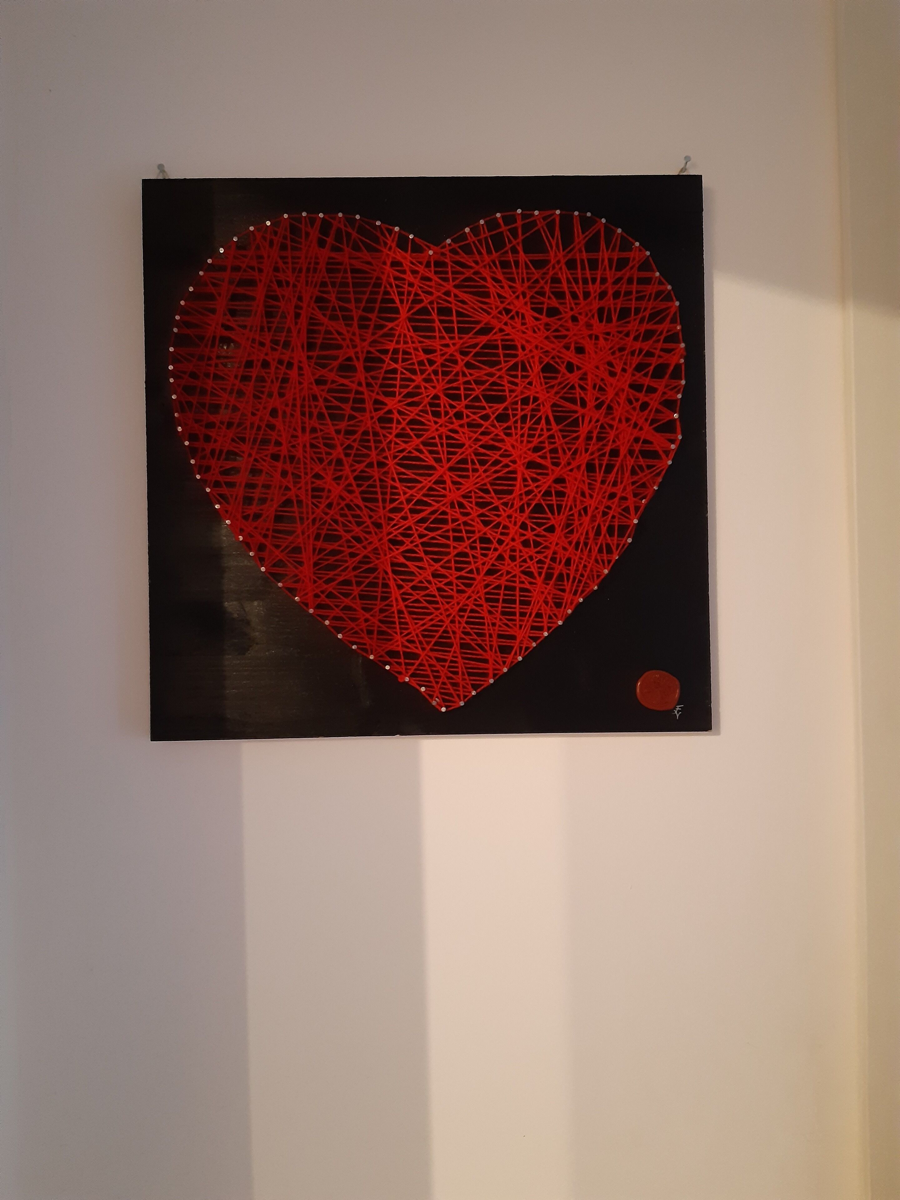 Una obra de arte con forma de corazón, en una gama de colores rojo y negro.