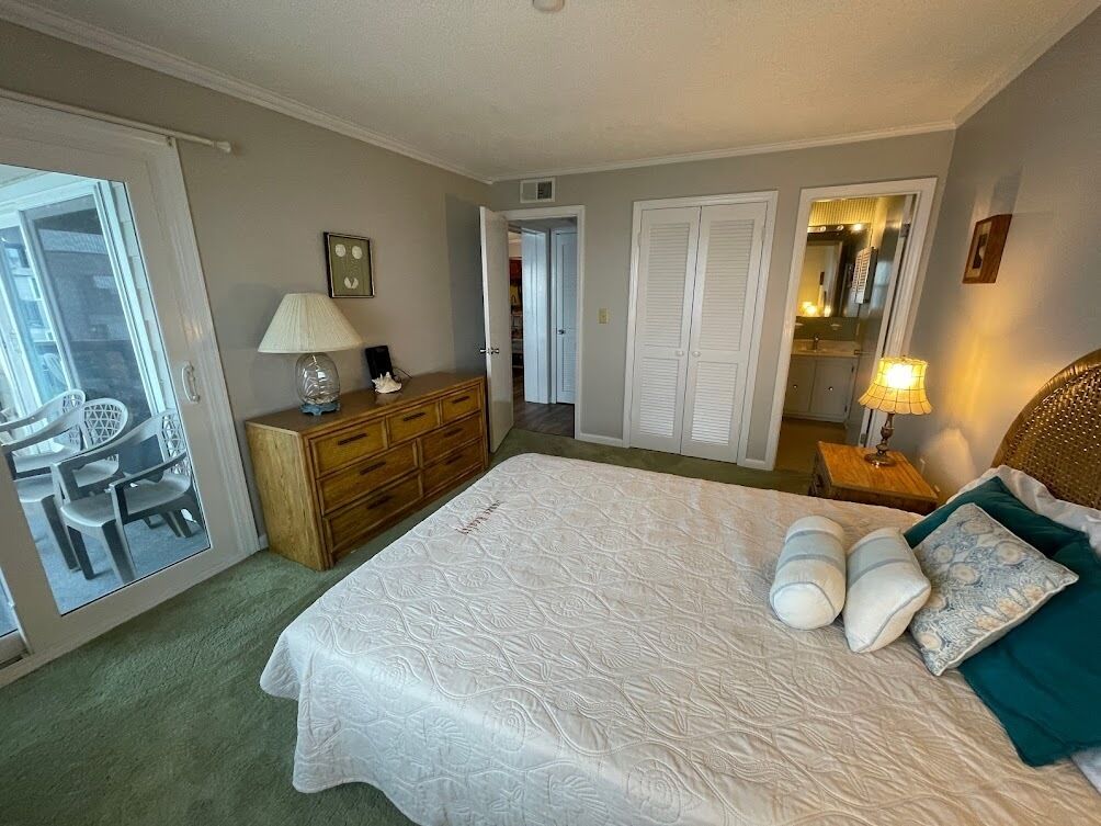 Ein Schlafzimmer mit einem großen Bett, einem Schminktisch, einem Sessel und einem Spiegel.