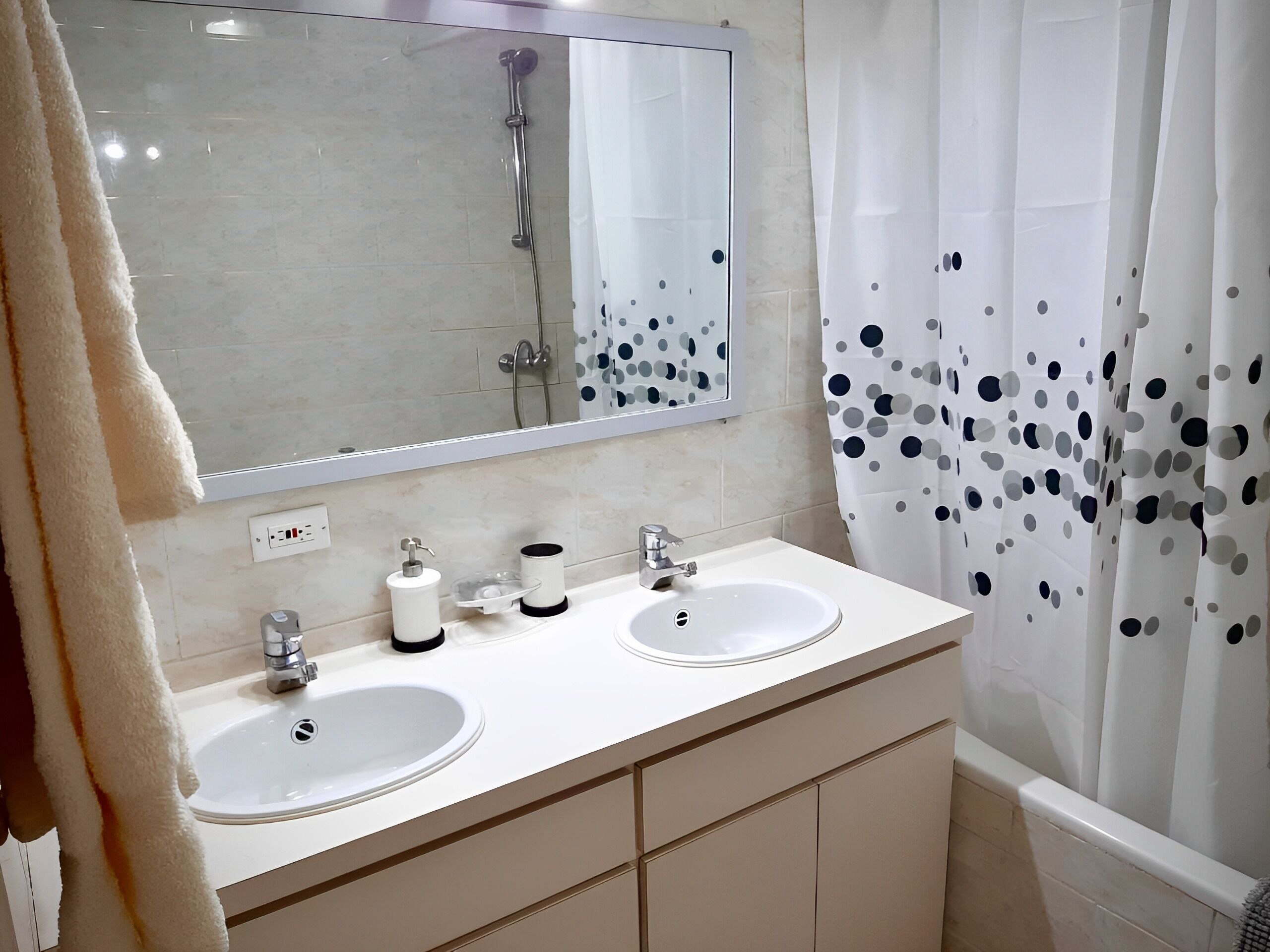 A bathroom with two sinks, a mirror, and a shower.