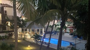 A pool area with lounge chairs and palm trees. - Cozy one-bedroom & mezzanine apartment (Philipsburg)