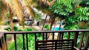 A wooden deck with a bench, overlooking a swimming pool surrounded by lush tropical vegetation. - Cozy one-bedroom & mezzanine apartment (Philipsburg)