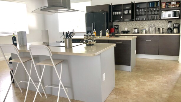 A modern kitchen with a central island, dark cabinetry, and a large window providing natural light. - Home in Fort Lauderdale (Fort Lauderdale)