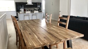 A modern kitchen with dark cabinets, a white island, and a dining area with a wooden table and chairs. - Home in Fort Lauderdale (Fort Lauderdale)