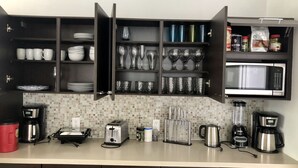 A modern kitchen with dark cabinetry, a microwave, a coffee maker, and various kitchen appliances. - Home in Fort Lauderdale (Fort Lauderdale)