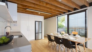 Une cuisine moderne avec des poutres en bois, un réfrigérateur en acier inoxydable et un coin repas avec une table dressée pour quatre personnes.