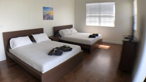 Ein Hotelzimmer mit zwei Betten, einem Bild an der Wand und einem Fenster mit Jalousien.