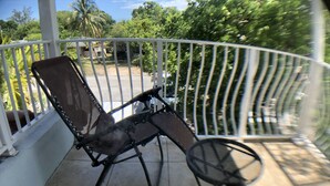 Ein Balkon mit Stuhl und kleinem Tisch, umgeben von einem weißen Geländer.