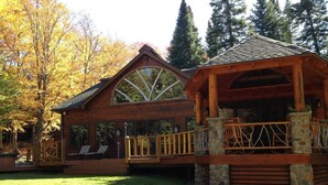 A wooden cabin with a covered deck and a stone foundation.