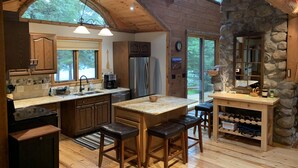 A spacious kitchen with wooden cabinets, a large island, and a stone accent wall.