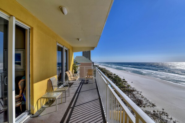Enjoy the ocean view from this balcony with a table and chairs.