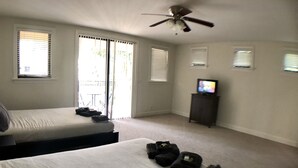 A bedroom with two beds, a ceiling fan, a television on a stand, and a view of the outside through the windows. - Huge House in Fort Lauderdale - 819 (Fort Lauderdale)