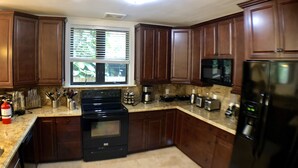 A kitchen with wooden cabinets, a stove, microwave, and refrigerator. - Huge House in Fort Lauderdale - 819 (Fort Lauderdale)
