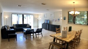 A modern living room with a sofa, dining table, and chairs. There is a kitchen area with cabinets and a TV. - Huge House in Fort Lauderdale - 819 (Fort Lauderdale)