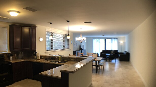 A modern kitchen with dark wood cabinets, a granite countertop, and pendant lighting. - Huge House in Fort Lauderdale -  821 (Fort Lauderdale)