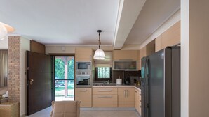 Eine moderne Küche mit Essbereich, ausgestattet mit Kühlschrank, Mikrowelle, Backofen und einem großen Fenster.
