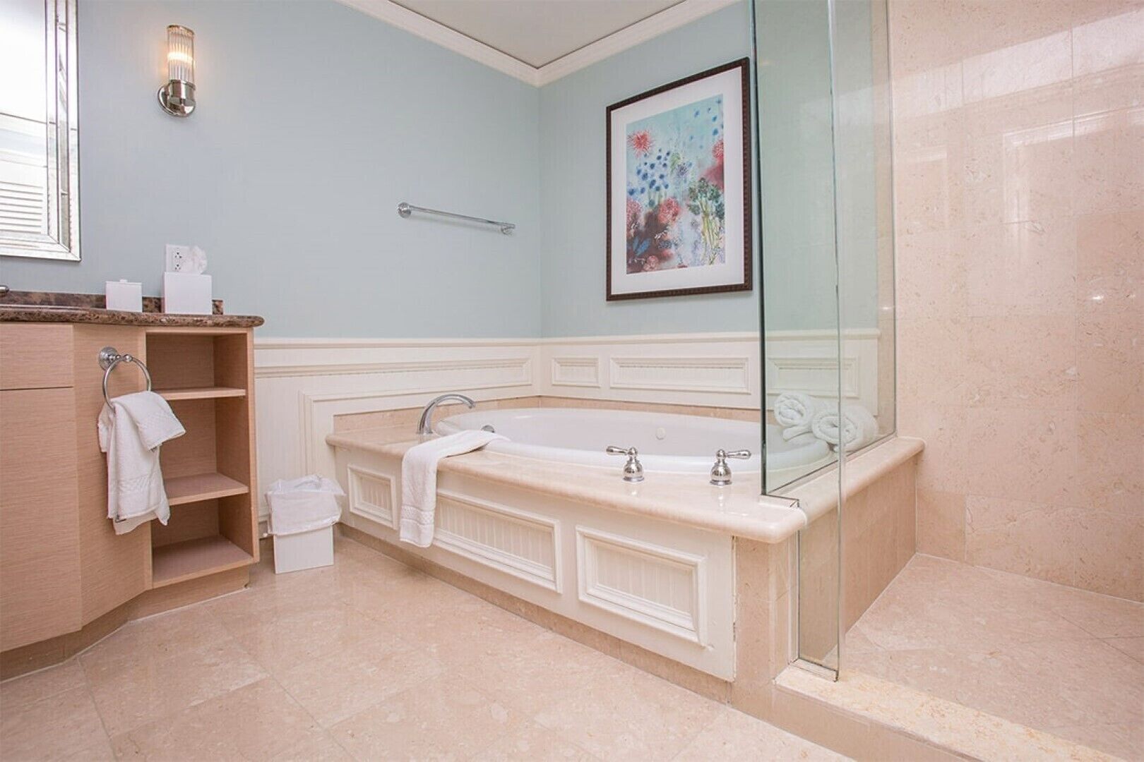 Une salle de bain avec une baignoire sur pieds, un meuble-lavabo avec un porte-serviettes, une œuvre d’art encadrée au mur et une cabine de douche en verre.
