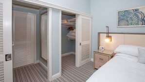 Habitació d'hotel amb llit, taulella de nit, armari amb portes corredisses i llum penjant a la paret.